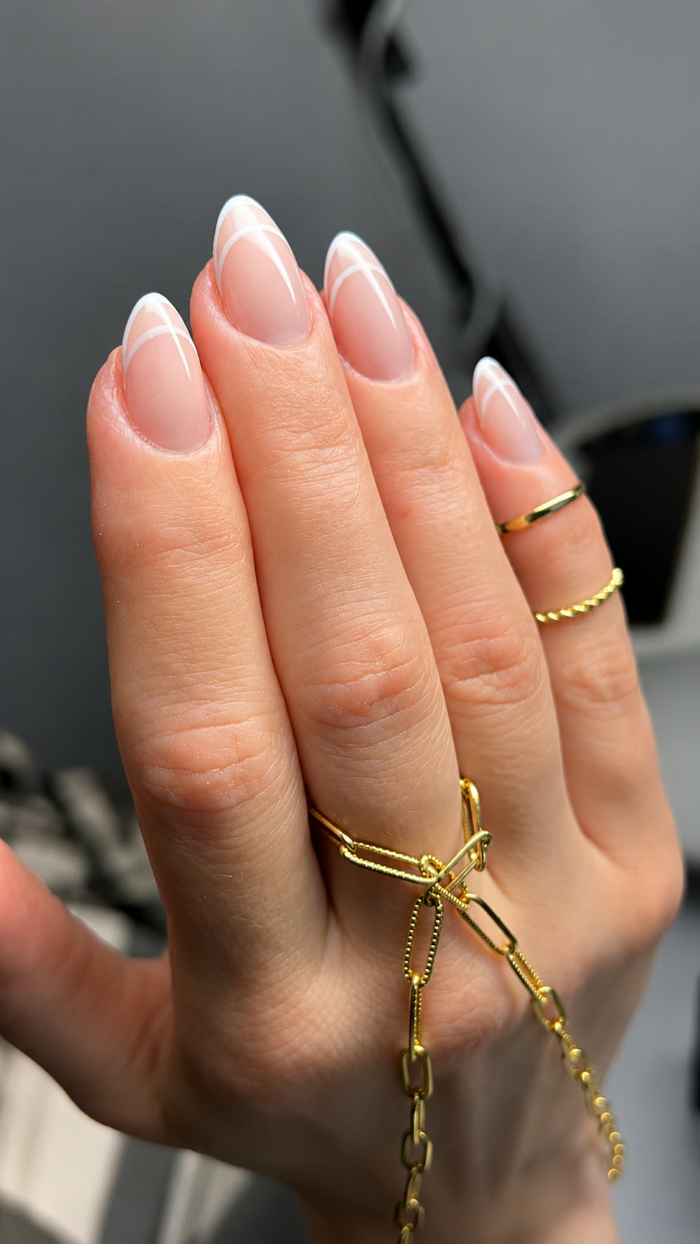 Soft French-tip almond nails with a delicate gold bracelet.