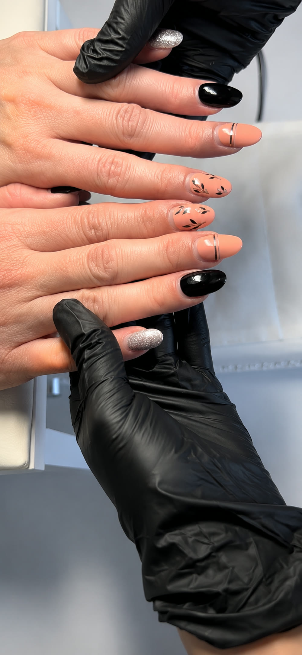 French manicure with fine dot accents, shown in the artist's gloved hands.