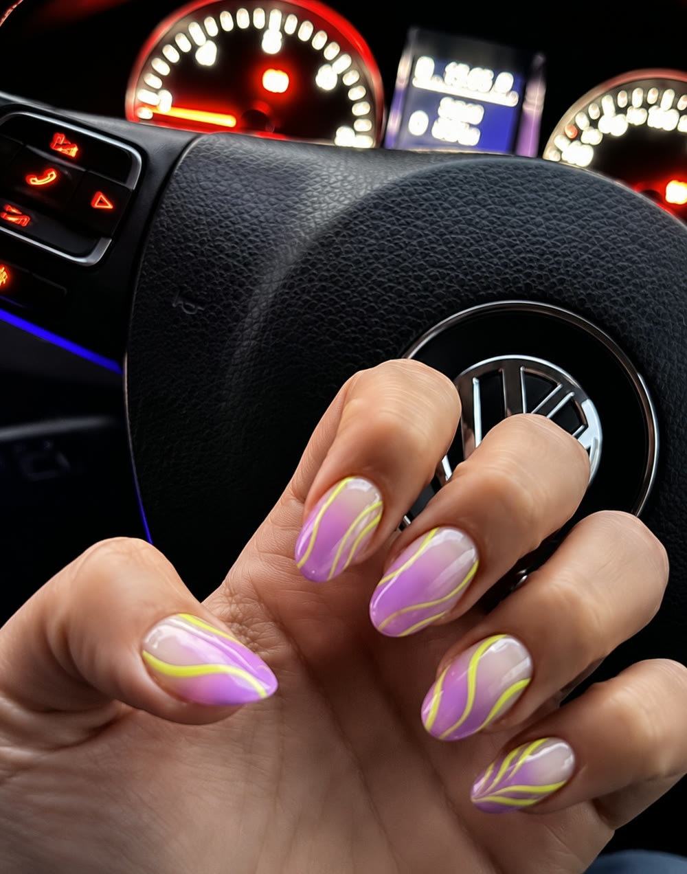 Pearl-swirl manicure resting on a car steering wheel.
