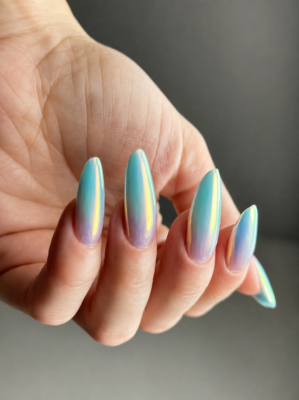 Iridescent pastel chrome nails in mint and lilac, on a relaxed hand.