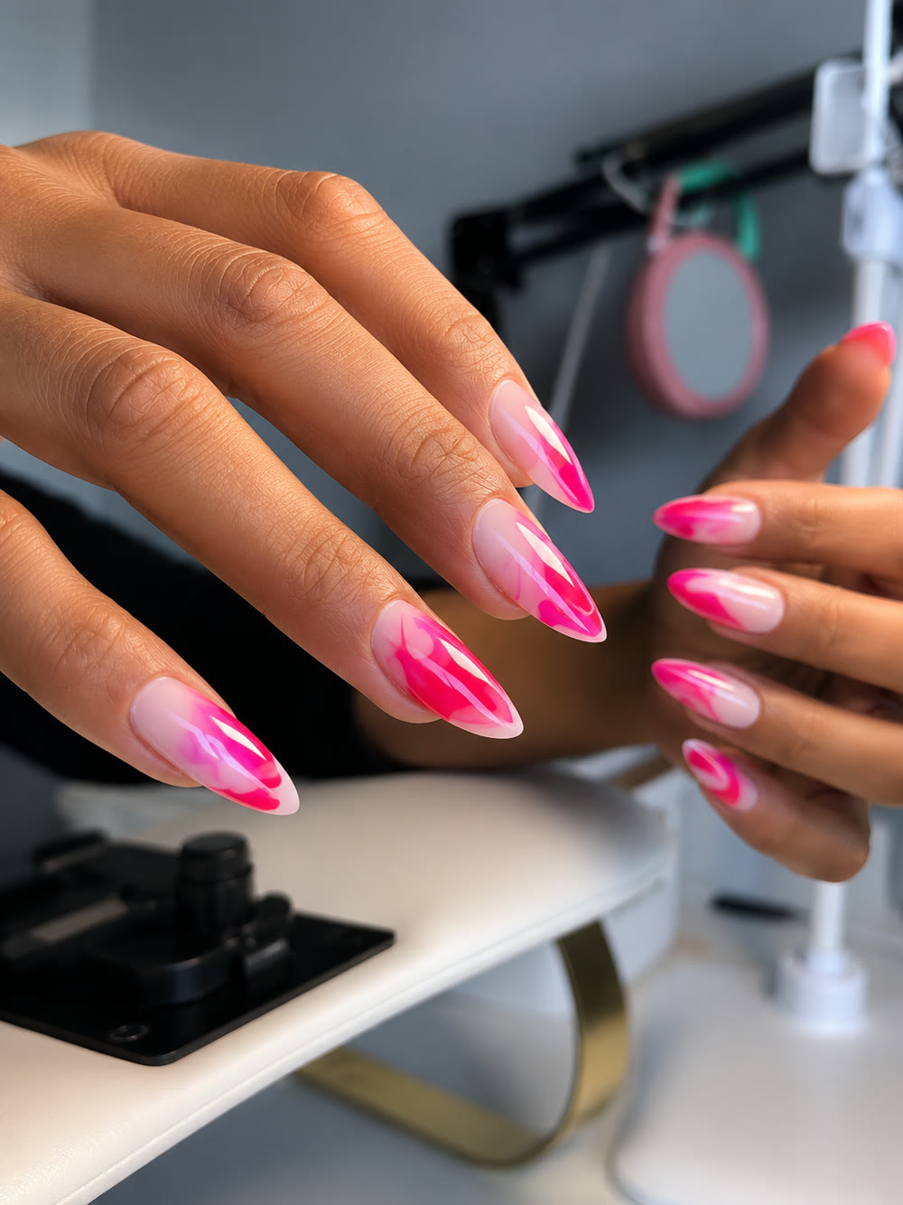 Bright pink airbrushed ombré almond nails, photographed at the studio table.