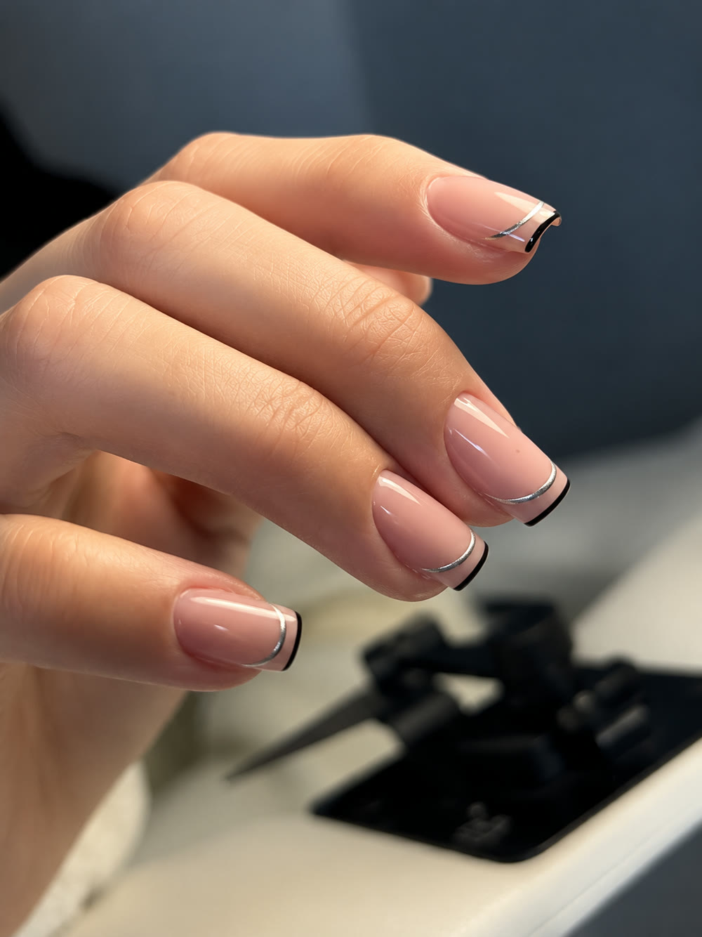 Sheer nude nails finished with a fine black outlined French tip.