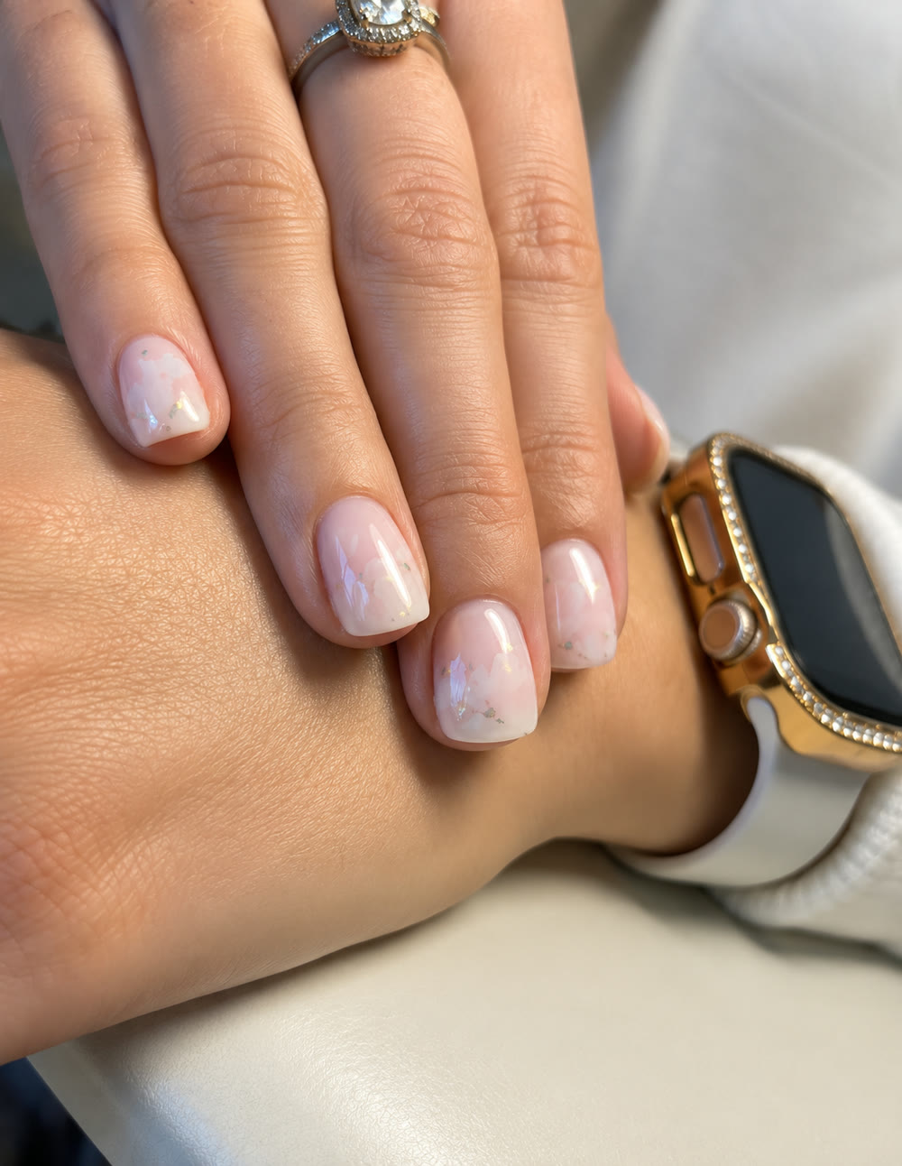 Pearl-white chrome nails on short square nails, worn with a ring and a gold watch.